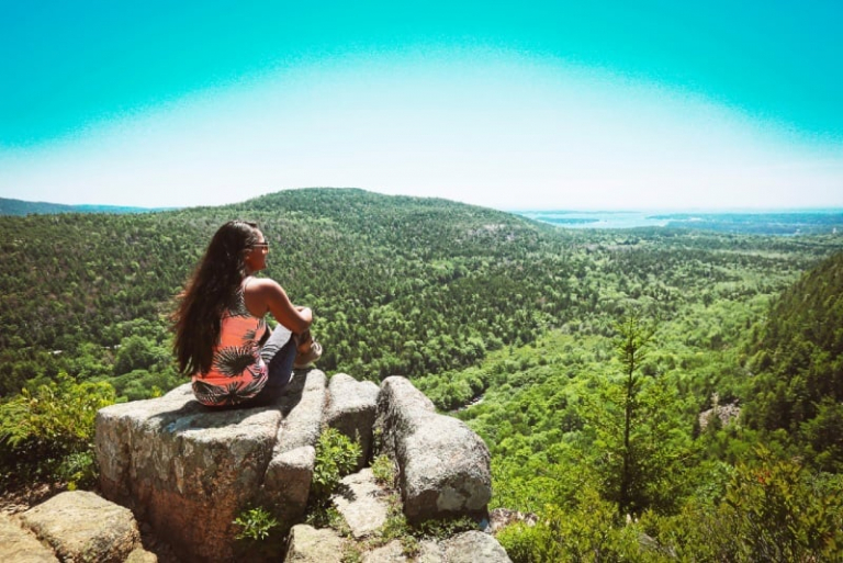 woman in orange top siting on rock