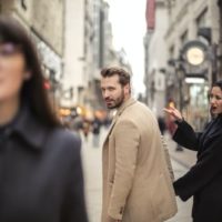 hombre mirando a mujer mientras se coge de la mano con otra mujer