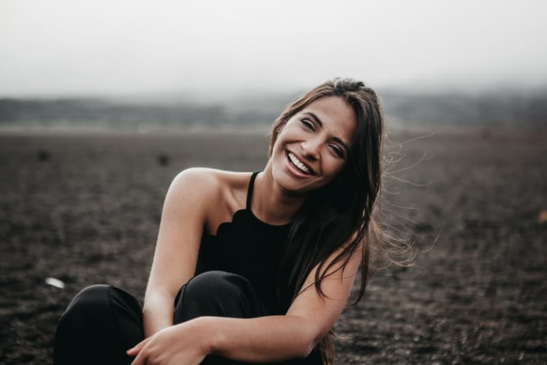 woman in black top smiling while sitting on ground