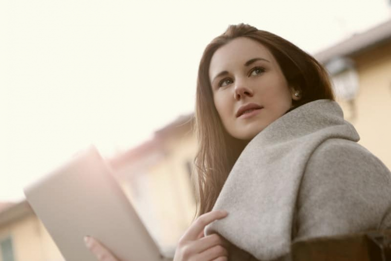 woman bringing a tab/laptop outdoors wearing thick coat