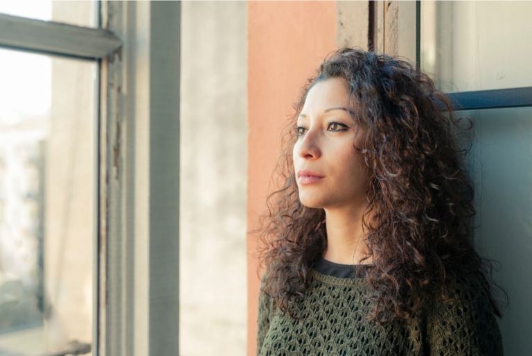 mujer mirando por la ventana de su casa