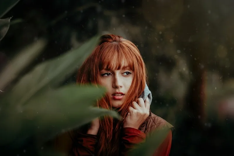 a sad red-haired woman standing outside in the rain