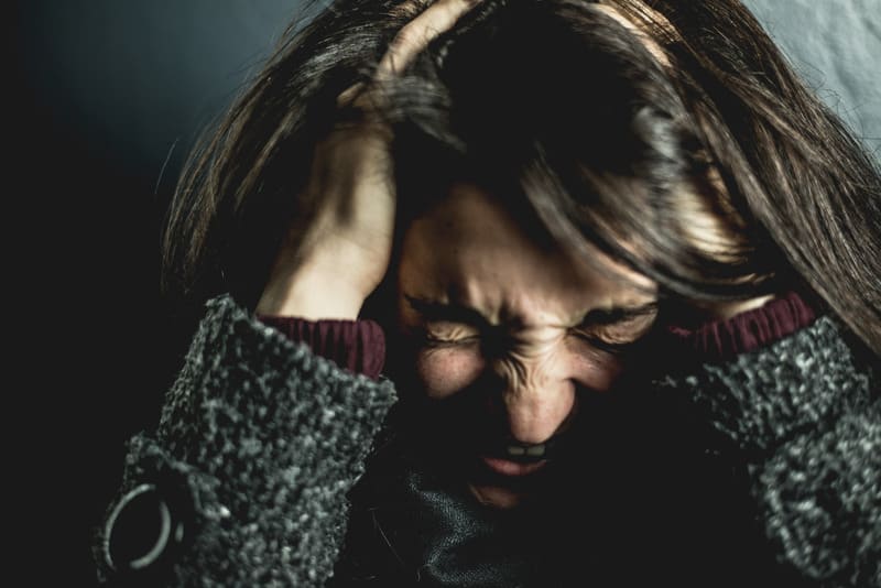 angry woman grasping her head wearing sweater with head in focus