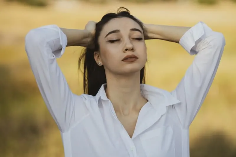 bothered young woman grasping her head wearing white blouse