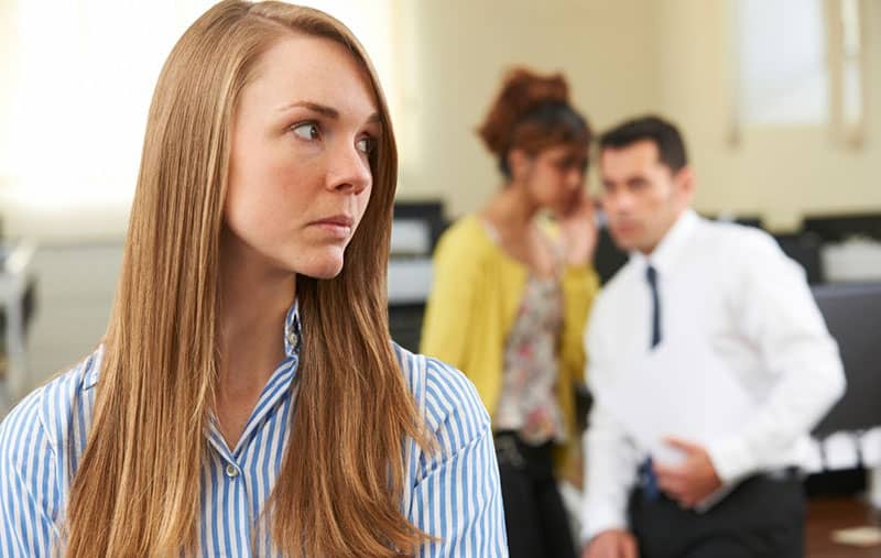 businesswoman being gossiped about by her male and female colleagues