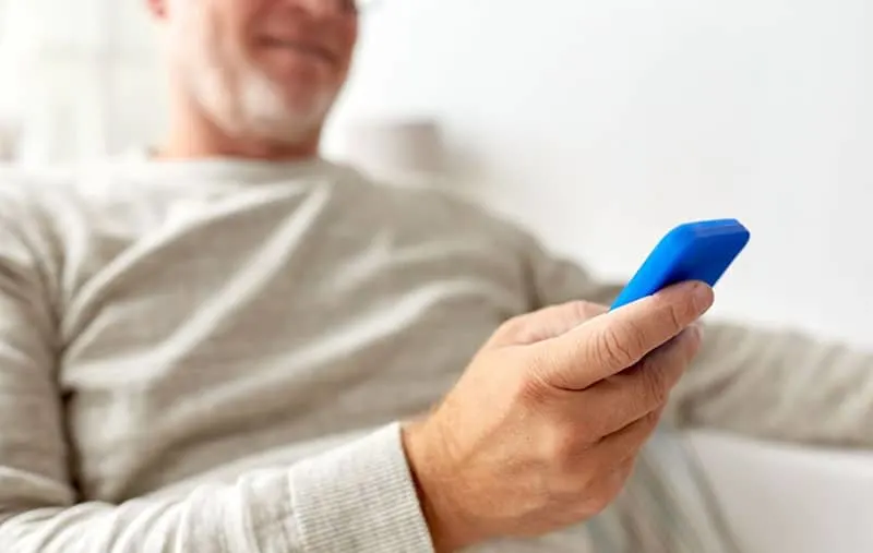 close up of old man texting inside home sitting