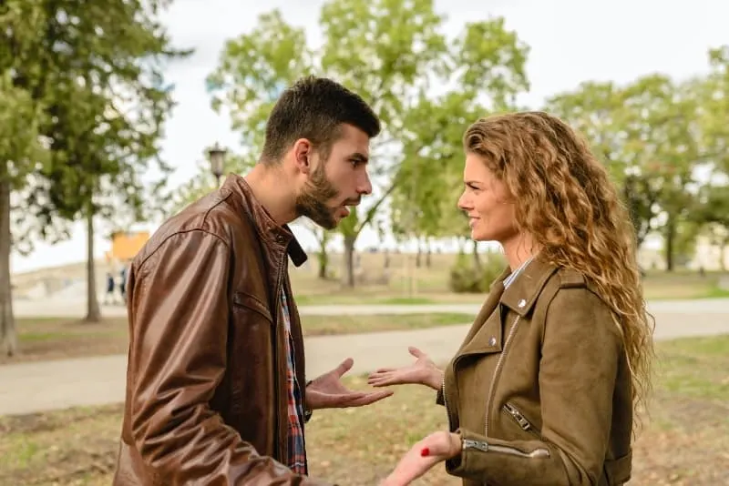 man in brown jacket and woman arguing outdoor