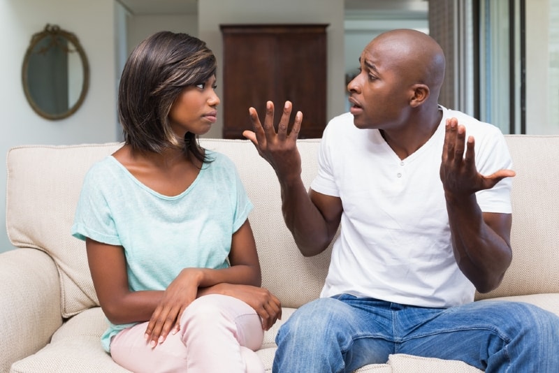 man and woman arguing while sitting on sofa