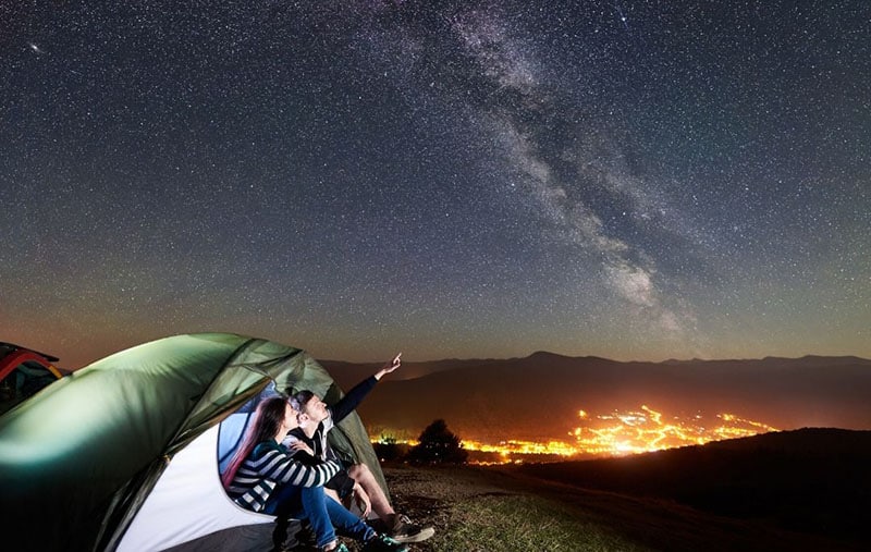 pareja de acampada observando las estrellas en el cielo durante la noche