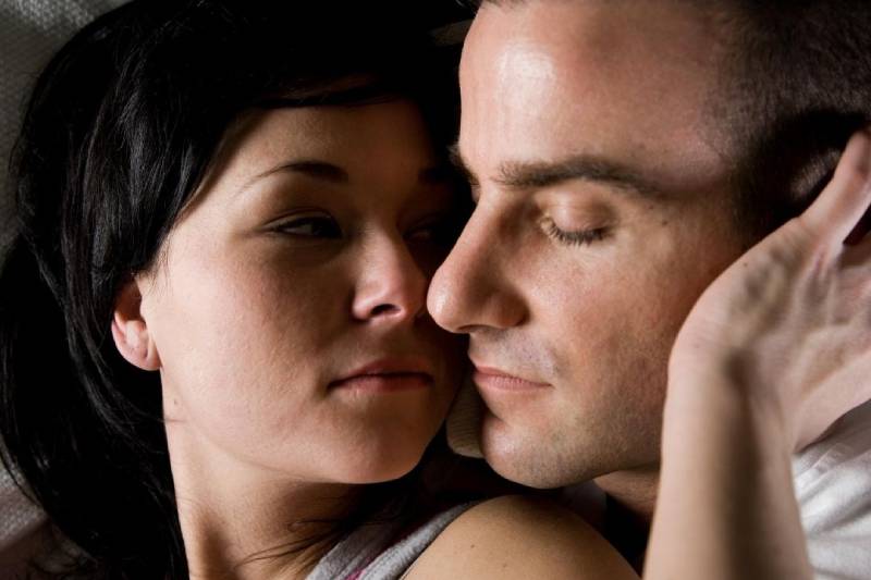 couple cuddling in bed woman touching man's face