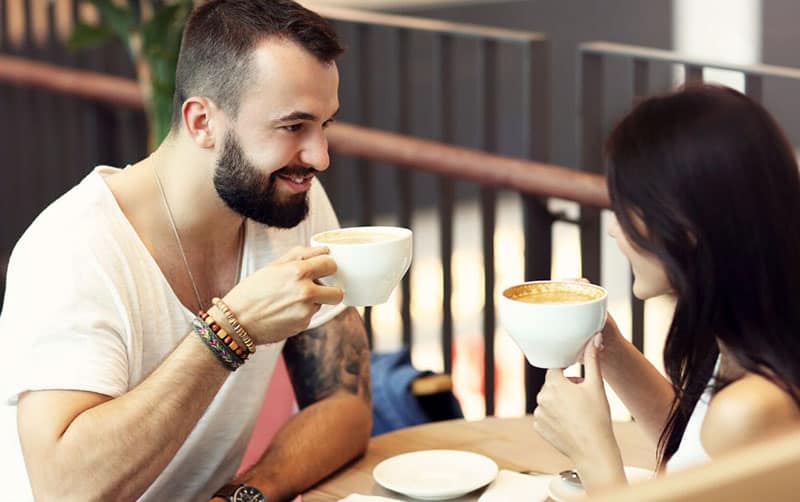 casal a fazer uma pausa para café à porta de um café