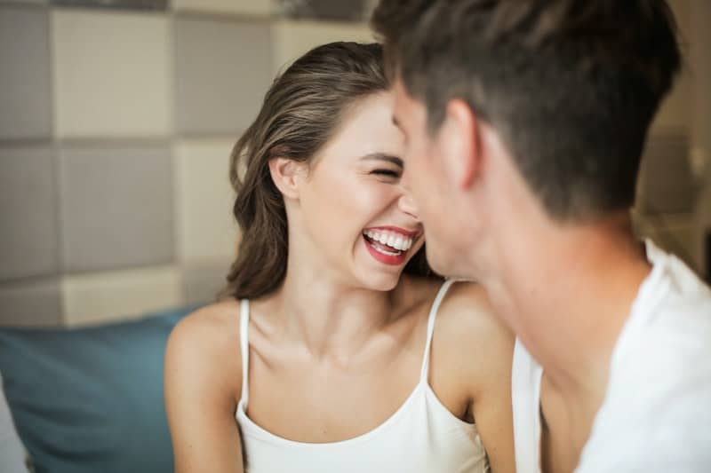 pareja riendo felizmente sentada dentro de la habitación