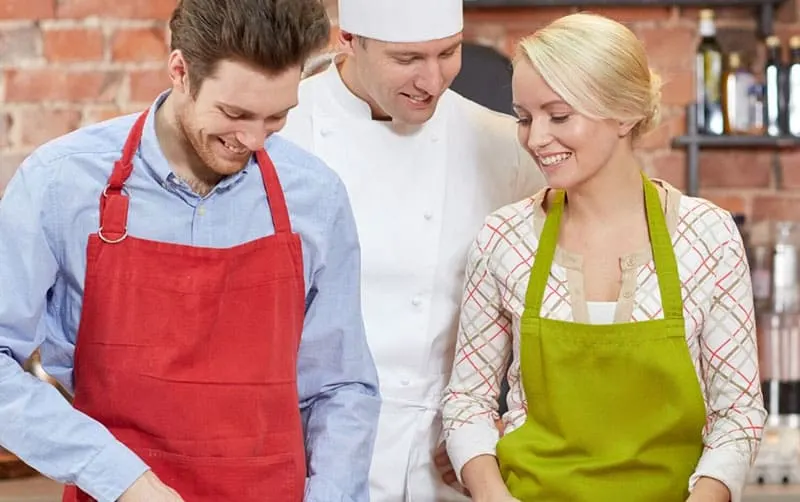 couple learn to cook supervised by a chef