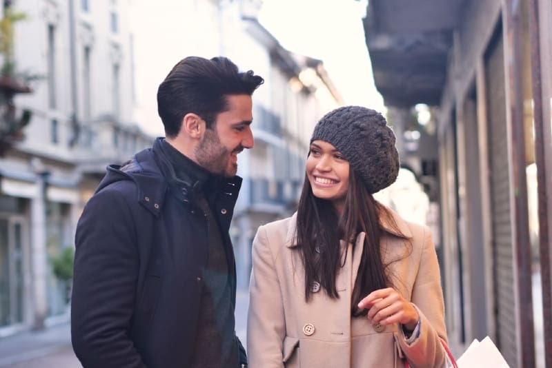 smiling man and woman making eye contact while standing outdoor