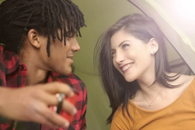 smiling man and woman making eye contact while sitting outdoor