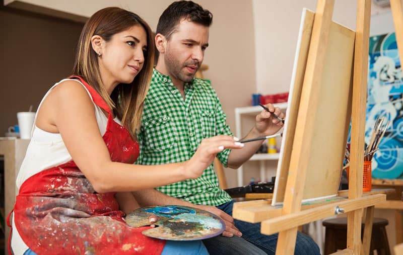 pareja de artistas pintando juntos en un lienzo