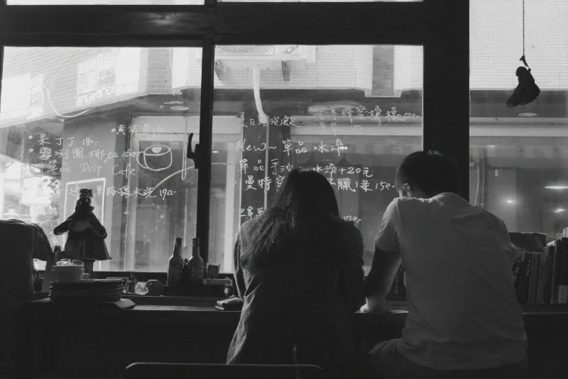 man and woman sitting in cafe near window