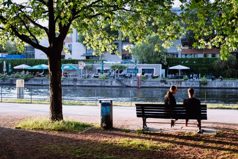 man and woman sitting on bench near water