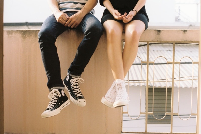 uomo e donna seduti su una recinzione di cemento