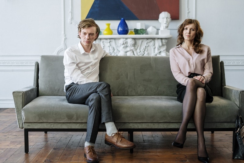 man in white shirt and woman sitting on sofa