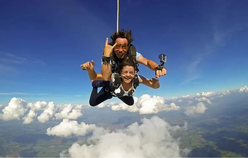 couple sky diving above white clouds