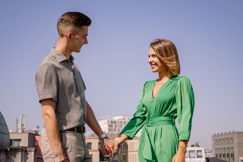 man and woman standing on rooftop and holding hands