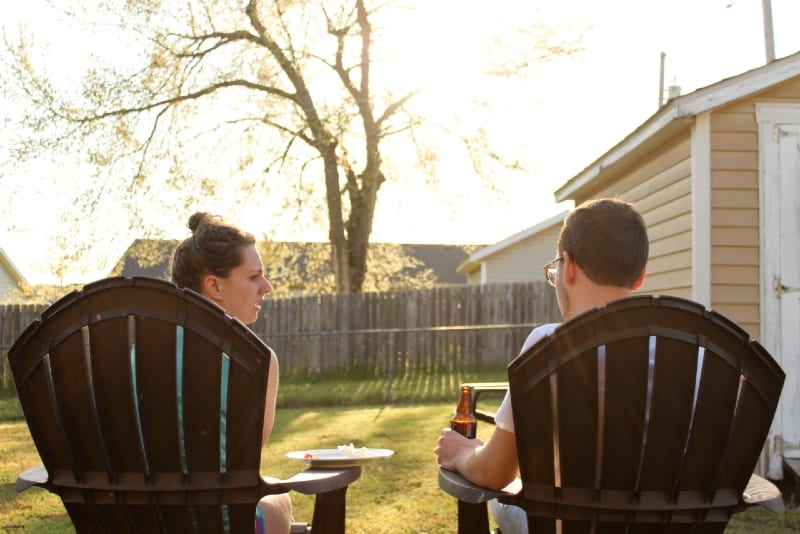 man and woman talking while sitting on chairs outdoor