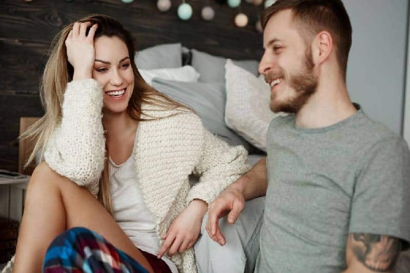 couple talking inside bedroom sitting on the floor beside bed