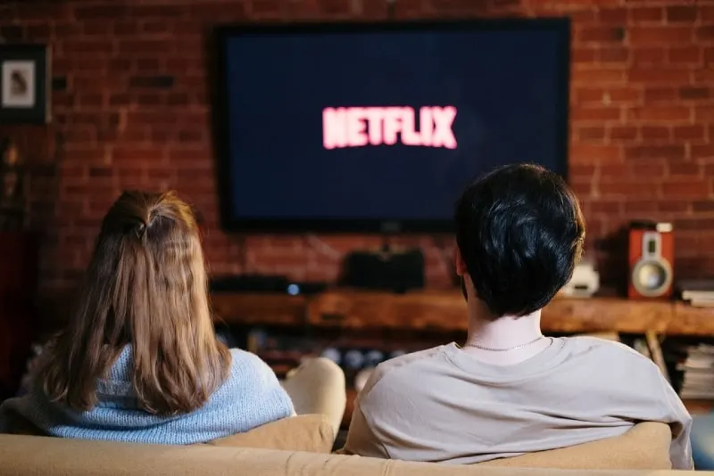 man and woman watching tv while sitting on sofa