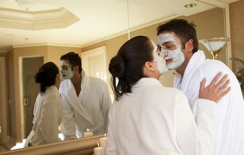 couple with facial mask kissing lips to lips inside the bathroom