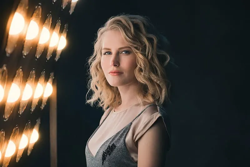 curly blonde haired woman near the many lights in a dark room
