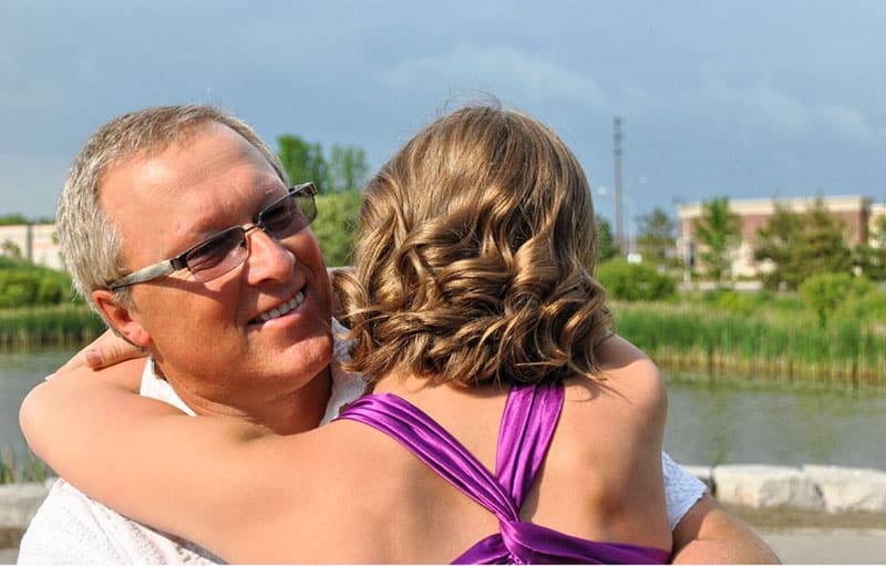daughter hugging father with happiness outdoors during the day