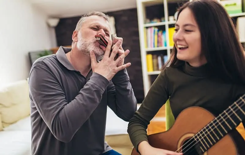 family having fun playing musical instruments harmonica and guitar