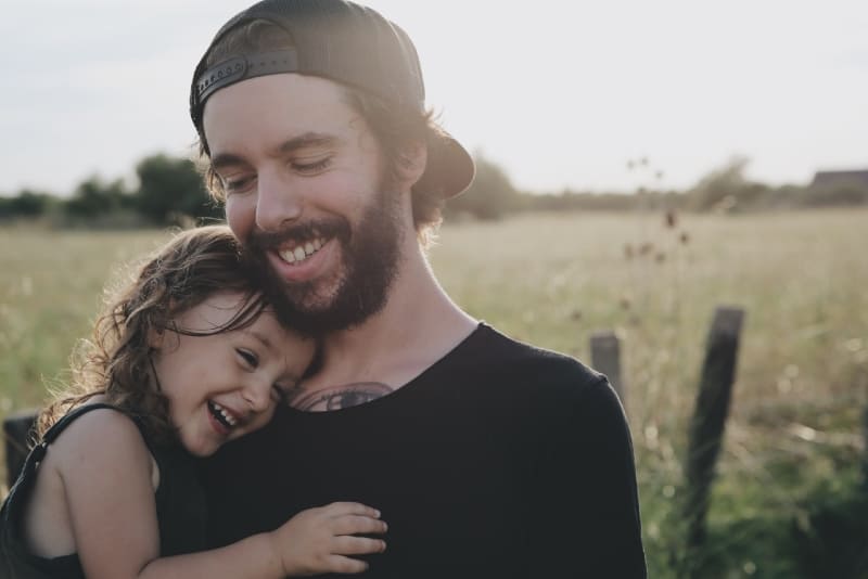 Pai de t-shirt preta com a filha ao colo ao ar livre