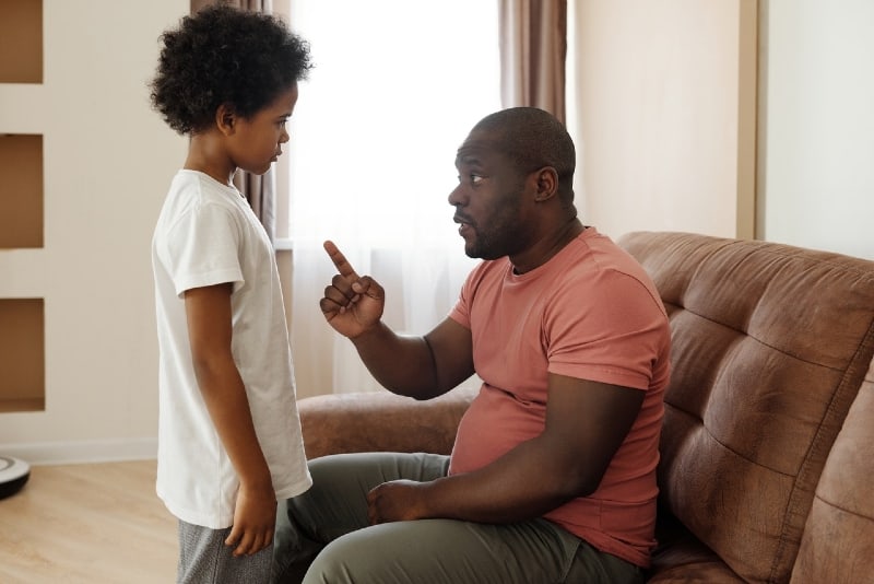 father talking to son while sitting on sofa