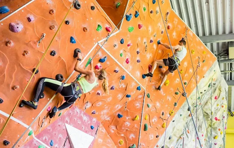 fit couple rock climbing indoors/ gym 