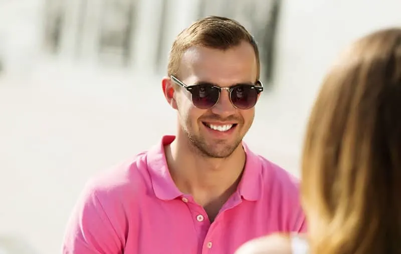 handsome man smiling, wearing pink shirt, in front of a woman 