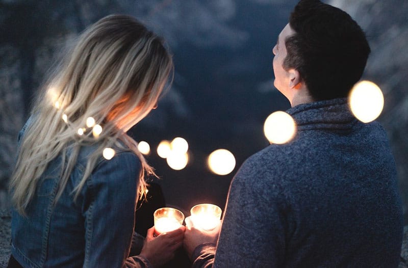 man and woman holding candles with series lights placed around them
