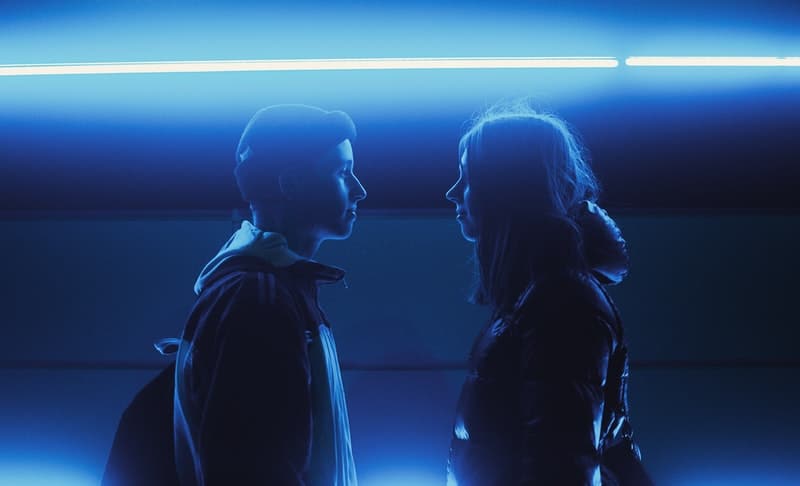 man and woman meeting in the street with blue straight lights above them