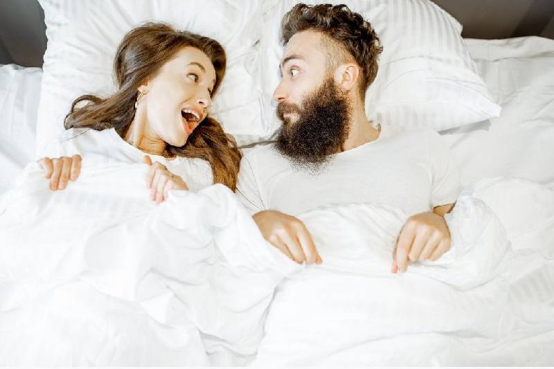 man and woman shocked at each other while lying in bed