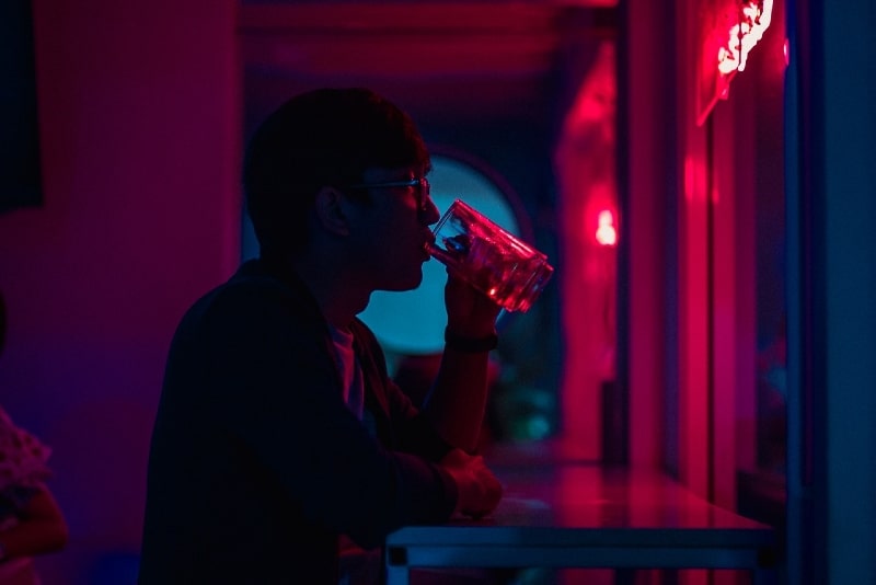 hombre bebiendo cerveza junto a la pared por la noche