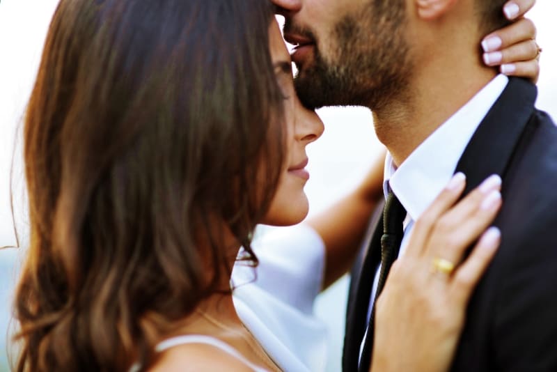 man in suit kissing woman's forehead