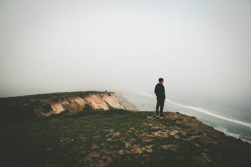 man in black jacket looking at ocean