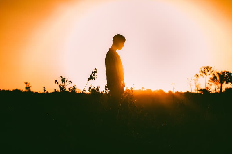 uomo in piedi sul campo durante il tramonto