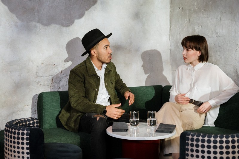 man talking to woman while sitting on green sofa