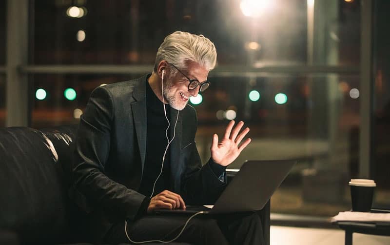mature businessman sitting and videocalling using his laptop