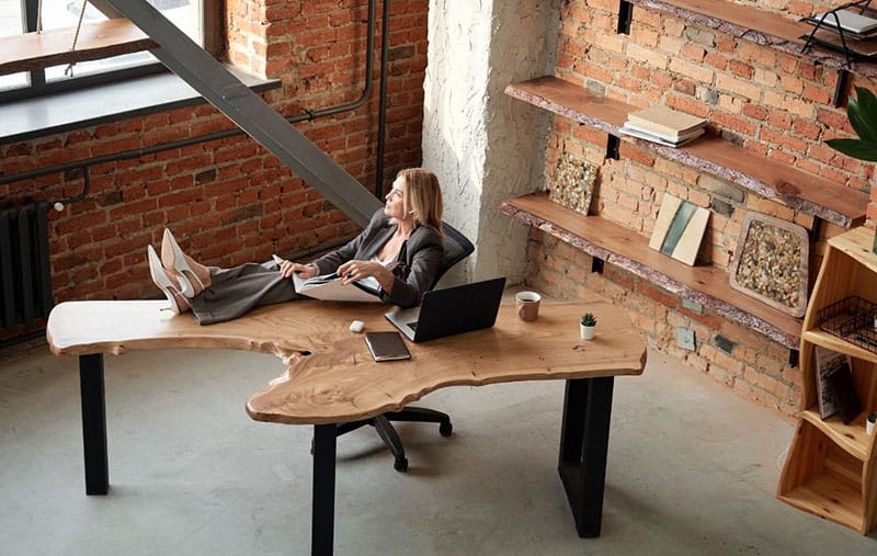 pensive woman working inside office with feet resting on the table