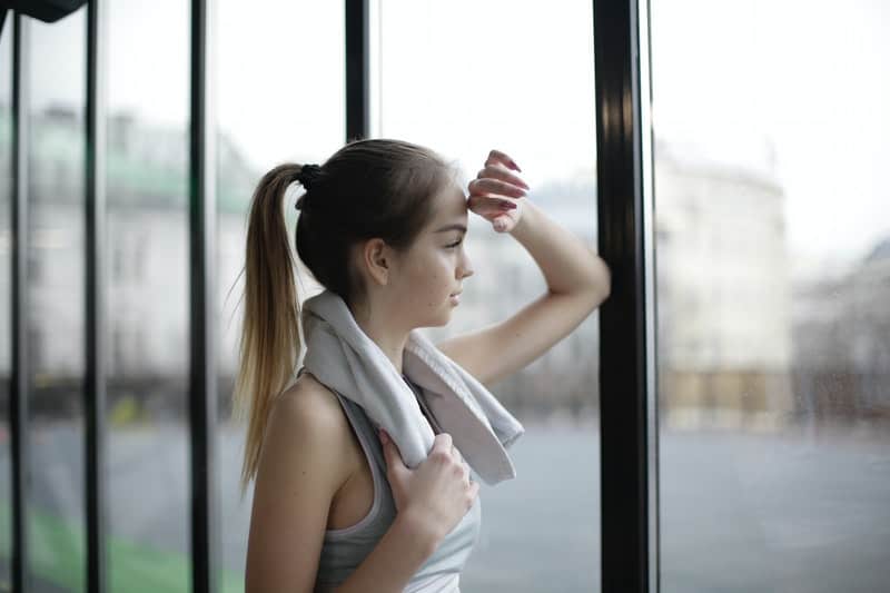 pensive young female looking out thru the glass wall wearing athletic wear