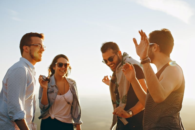 cuatro personas riendo de pie al aire libre