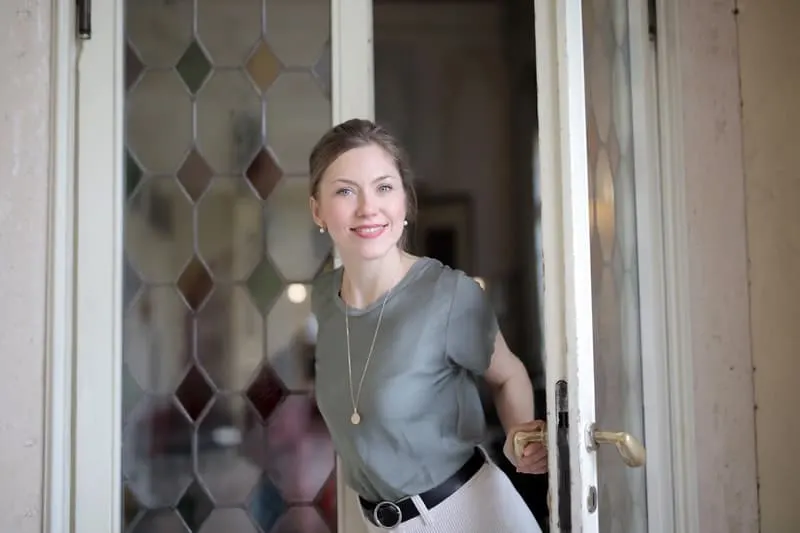 positive young woman entering the doors of an establishment smiling